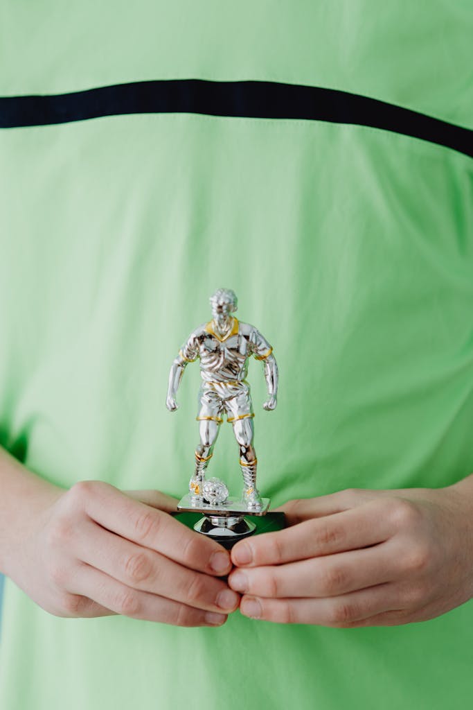 A child proudly holding a silver soccer trophy in a close-up image.