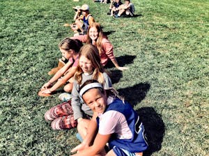 Group of children sitting in a grassy park, enjoying a sunny summer day together.